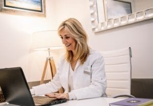 Cheerful doctor using laptop in office